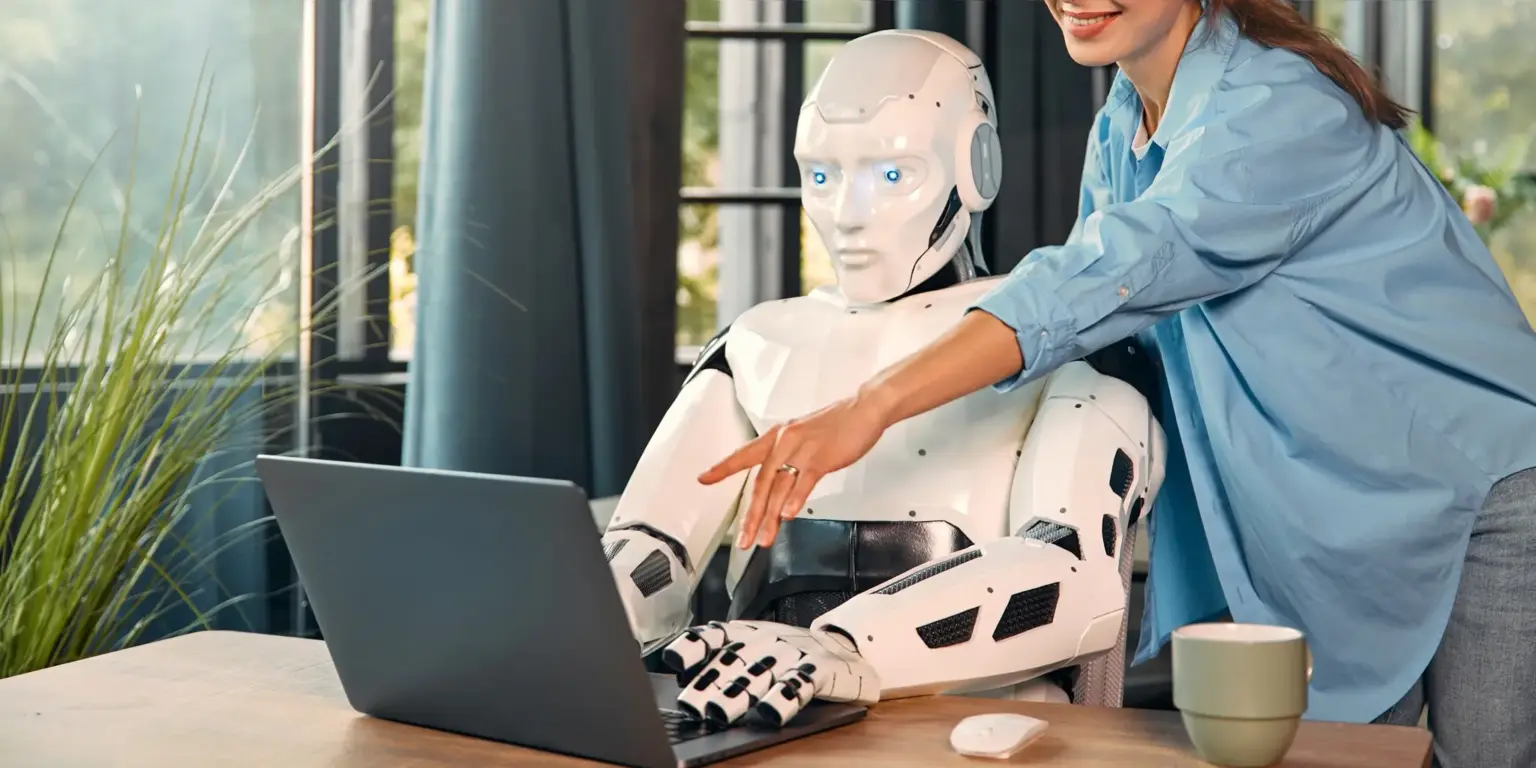 remyundremy newsletter_medical writing: wo künstliche Intelligenz noch versagt_ein Roboter mit Stethoskop sitz vor einem Laptop und eine Frau steht beim ihm und erklärt