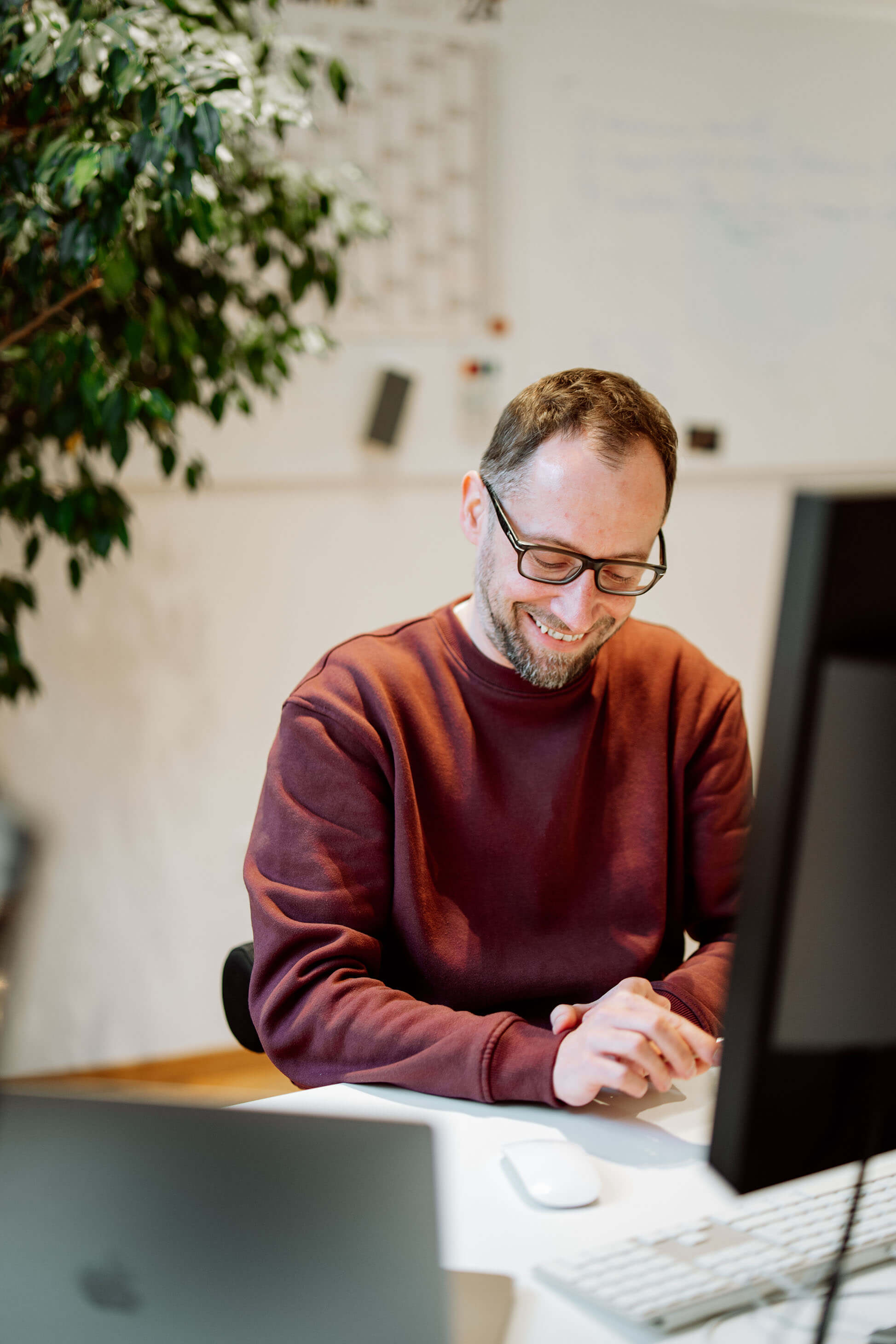 Lachender Designer von Remy & Remy im Agenturbüro während der Arbeit an Projekten für Healthcare-Marketing und Markenkommunikation