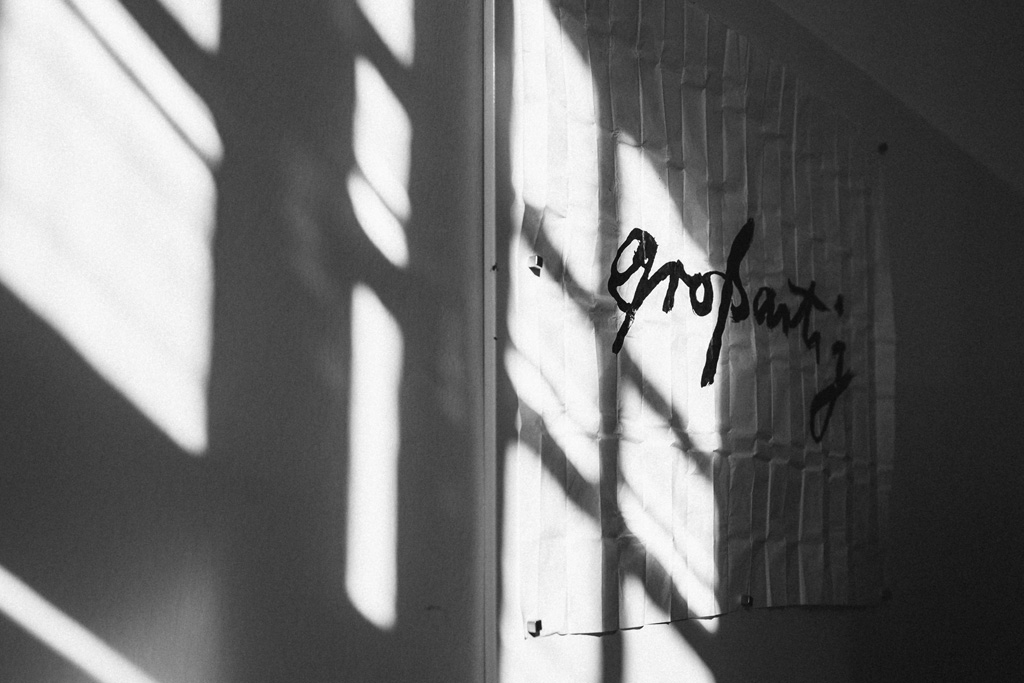 Weiße Wand mit geschwungener schwarzer Schrift ‚großartig‘ als inspirierendes Gestaltungselement im Büro