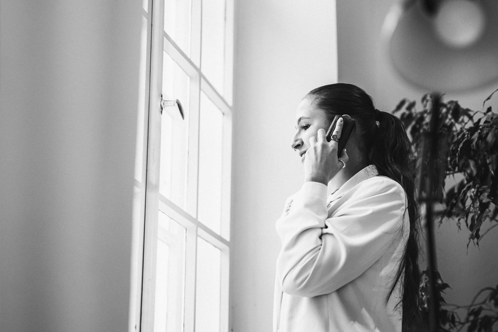 junge Mitarbeiterin die telefonierend aus einem großen Fenster im Büro blickt