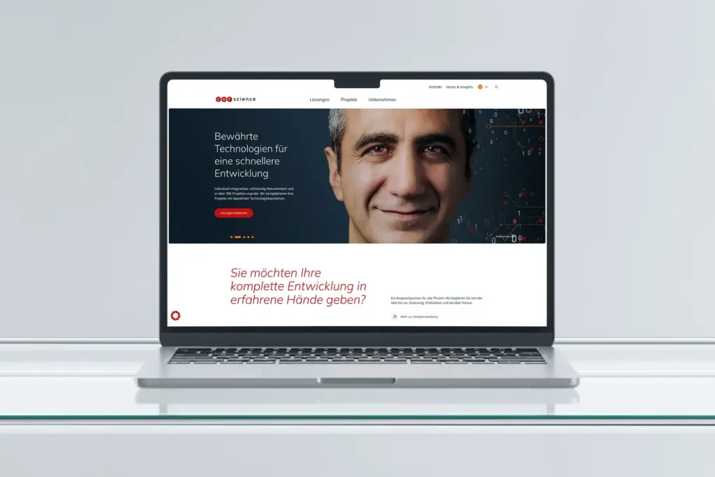 Referenzprojekt Corsience Corporate Design Relaunch - Mockup -Auf dem Laptop ist eine stationäre Landingpage zu sehen. Vor einem dunkelblauen Hintergrund ist ein Mann abgebildet. Rechts neben ihm sind die Ziffern „1“ und „0“ in unterschiedlichen Größen und Darstellungsformen angeordnet. Links befindet sich ein weißer Werbeslogan. Unter dem Gesicht des Mannes ist ein weißer Balken mit roter Schrift platziert.