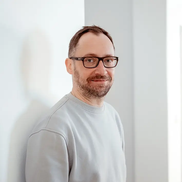 Portrait von Mitarbeiter mit schwarzer Brille und Bart tätig als Artdirektor bei Remy & Remy Healthcare Kommunikation