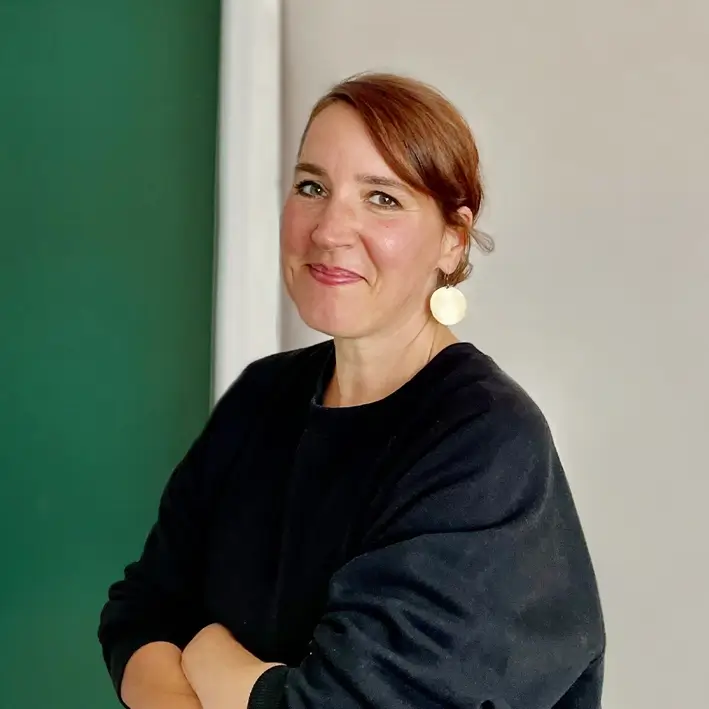 Porträt von Mitarbeiterin vor grüner Wand tätig als Artdirektorin im Remy & Remy Team