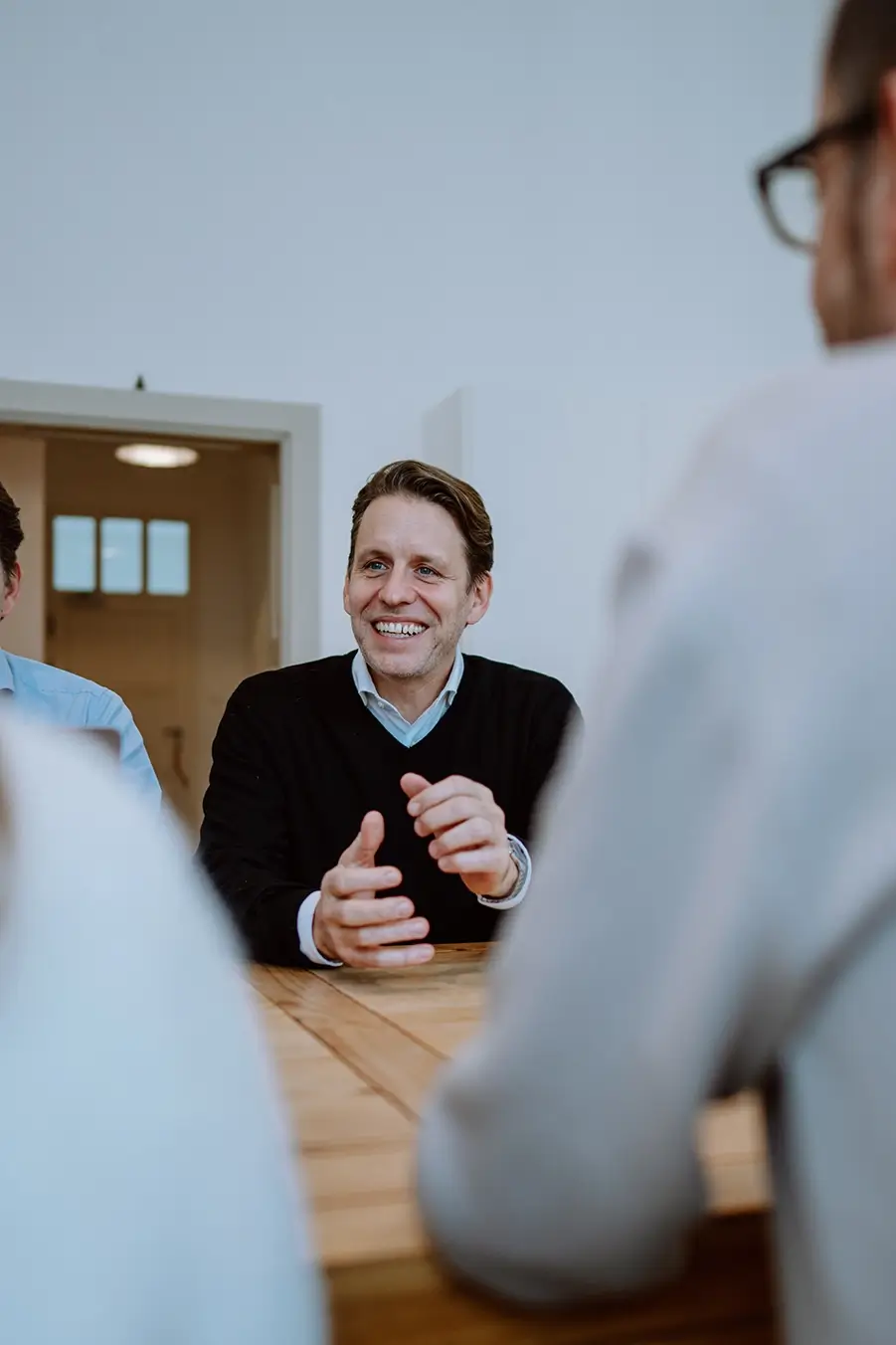 Geschäftsleitung im freundlichen Austausch mit dem Team während eines aktiven Meetings zur Entwicklung von Marken- und Kommunikationsstrategien im Healthcare-Bereich