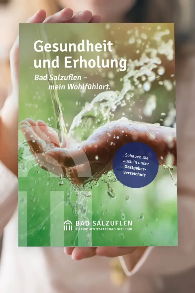 Referenzprojekt Bad Salzuflen - Mockup eines Werbemagazins mit großem Titelbild einer Hand, über die Wasser fließt, vor grünem Hintergrund. Oben links befindet sich ein Werbeslogan, unten links ein milchig-transparentes Wasserzeichen und unten mittig das Logo. In der Mitte des Deckblatts ist ein dunkelblauer, leicht transparenter runder Button mit weiteren Informationen zum Magazin platziert.